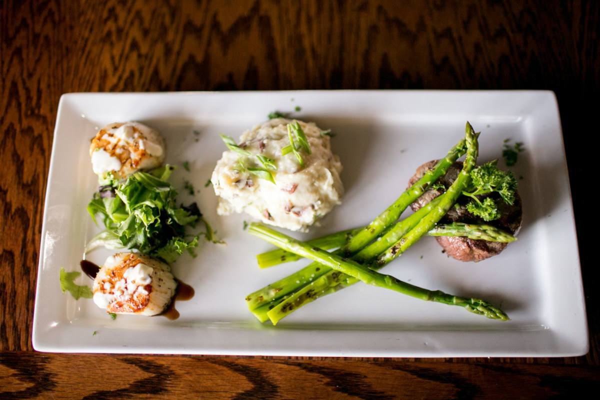 Scallops, steak and asparagus served on a white plate