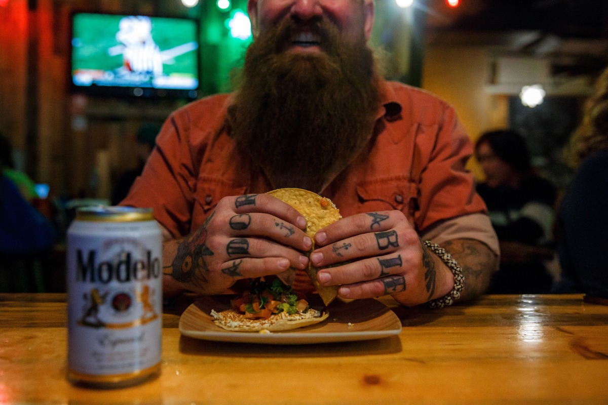 Interior, customer eating tacos and enjoying a can of Modelo beer