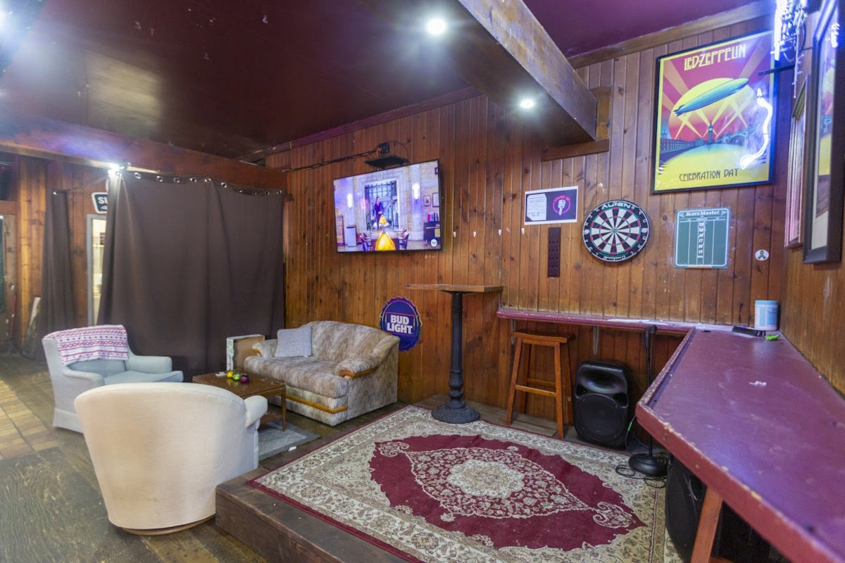 Interior, sofa seating and armchairs, TV screen, dartboard on the wal