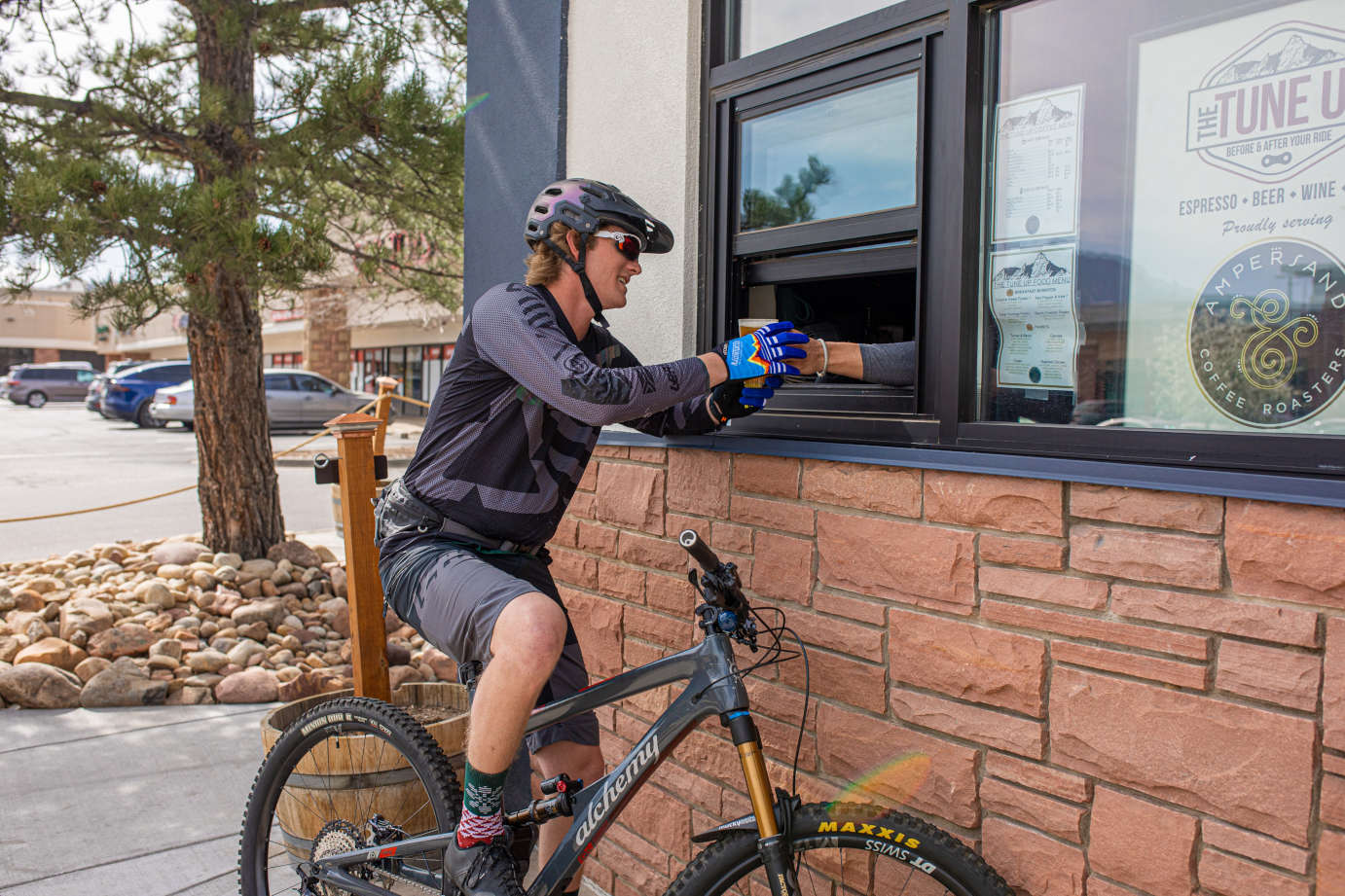Exterior, a cyclist taking a drink form the food order counter