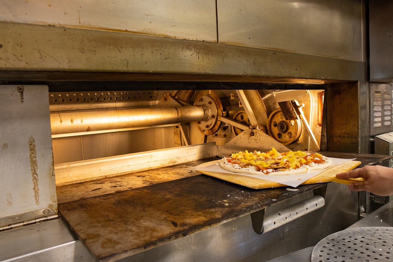 Employee placing pizza in the oven