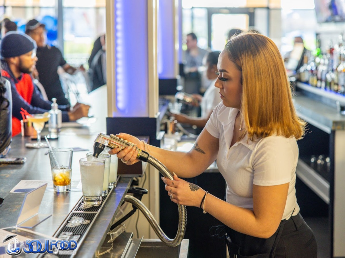 Bartender pouring drinks using a gun dispenser