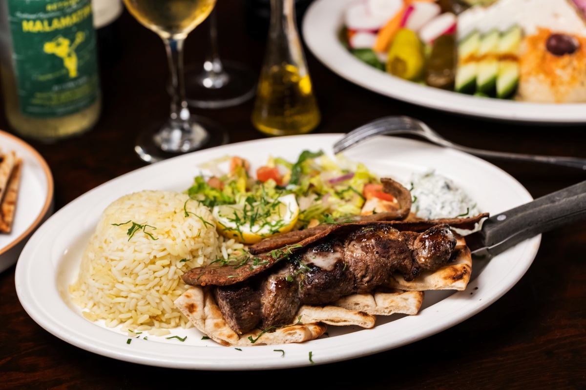 Grilled kebab platter with rice, pita, salad, and tzatziki