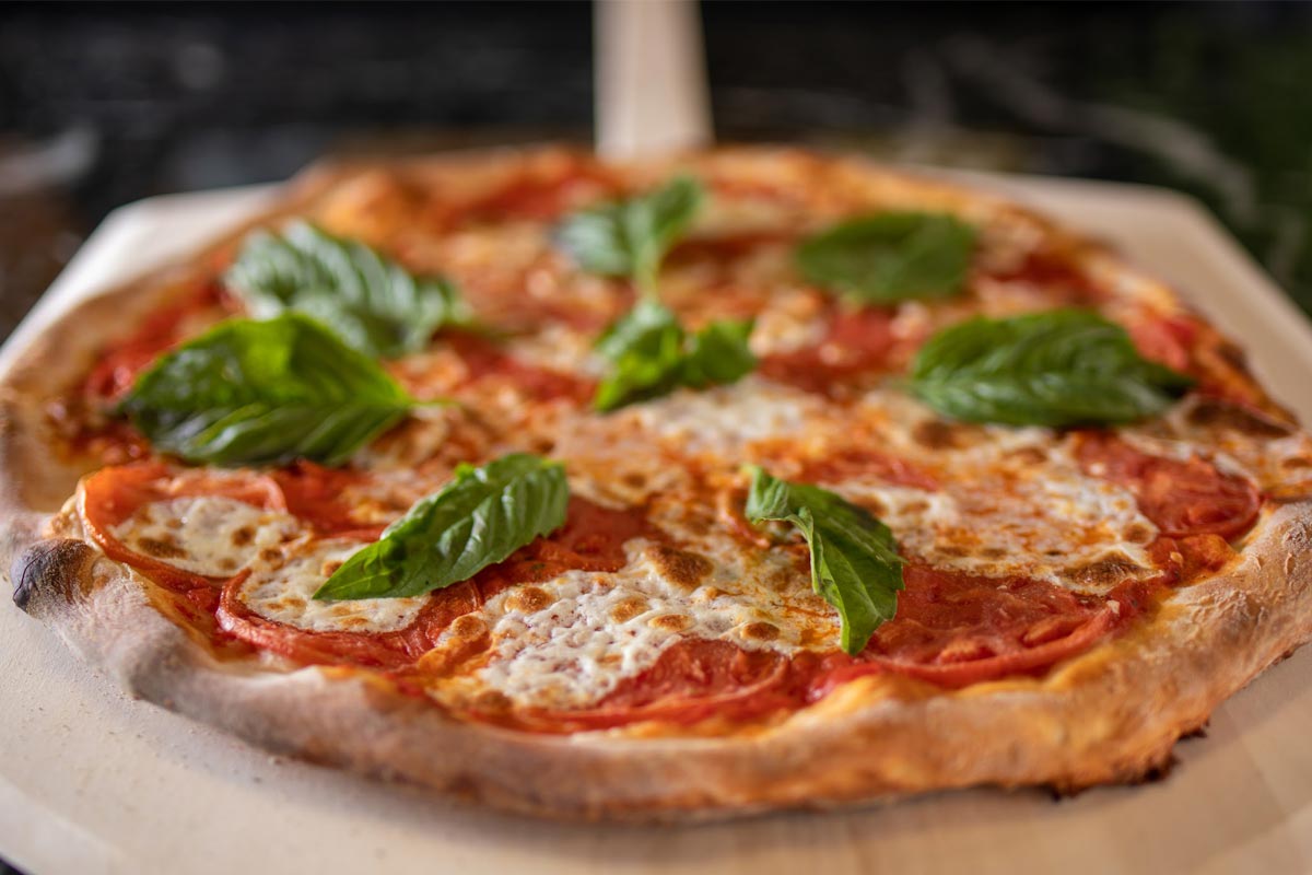 Pizza with mozzarella, tomato slices and fresh basil.