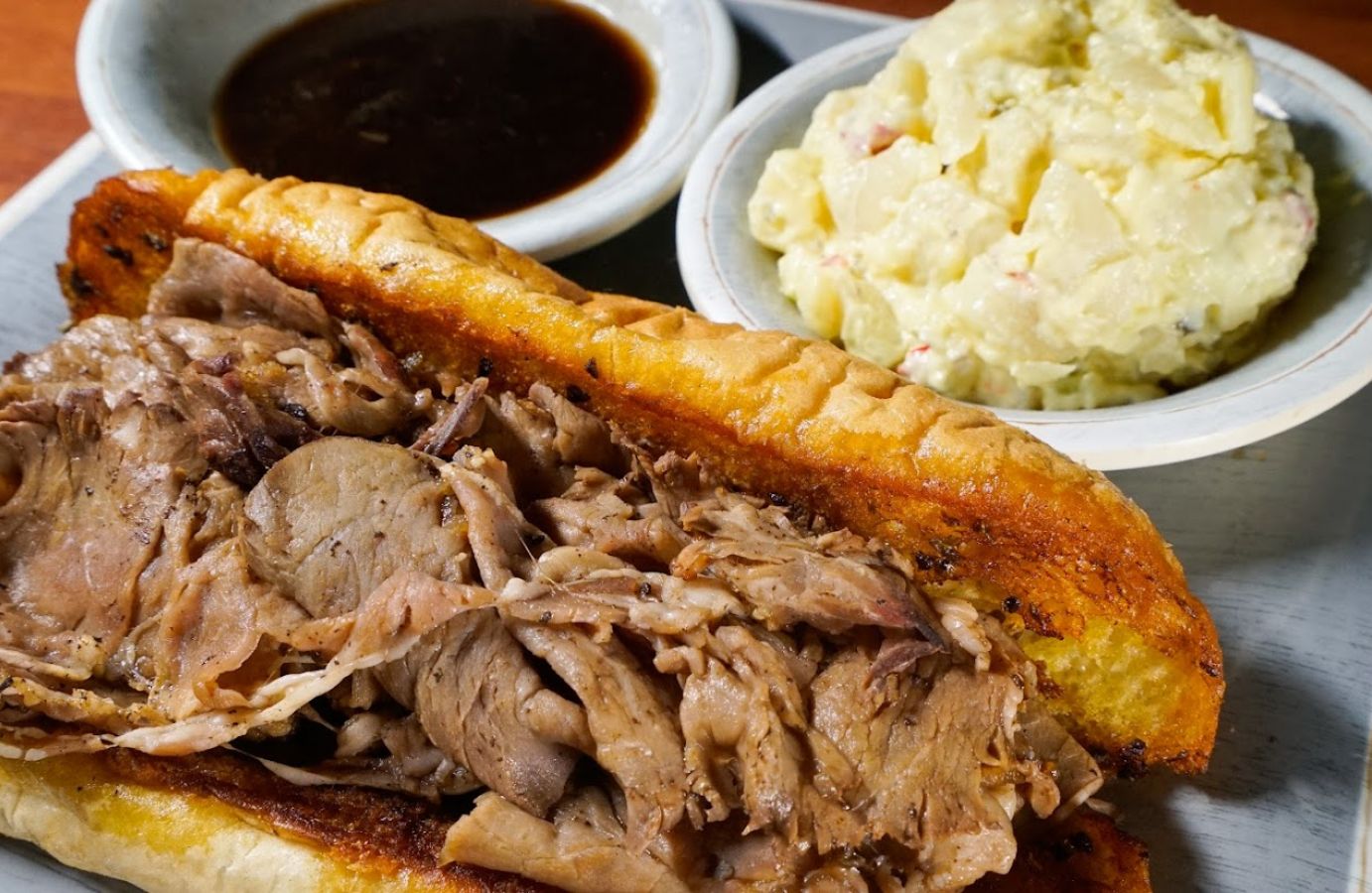 Closeup of a shaved prime rib sandwich with mash potatoes