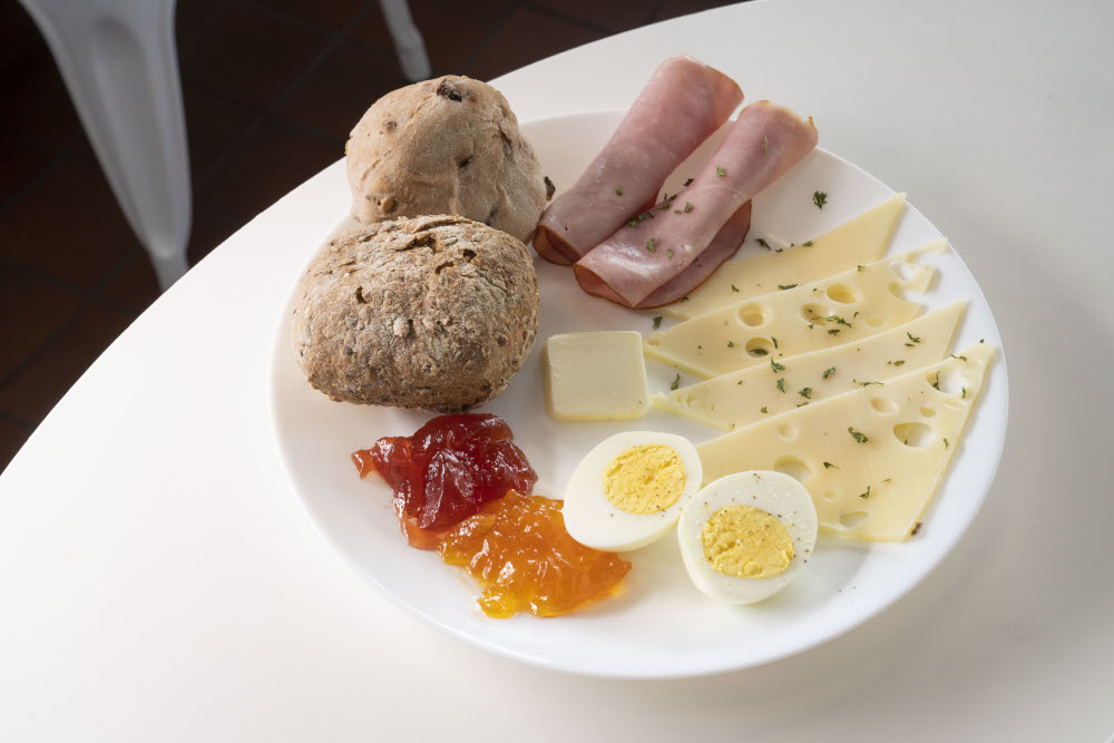 Breakfast plate, with sliced ham, Swiss cheese, boiled eggs, butter and jam