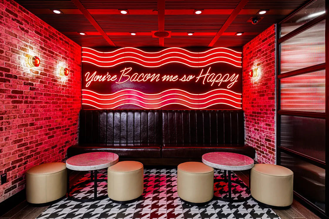 Restaurant interior with neon and brick designs.