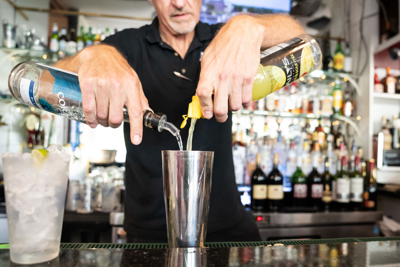 Bar, bartender pouring spirits into a steel shaker