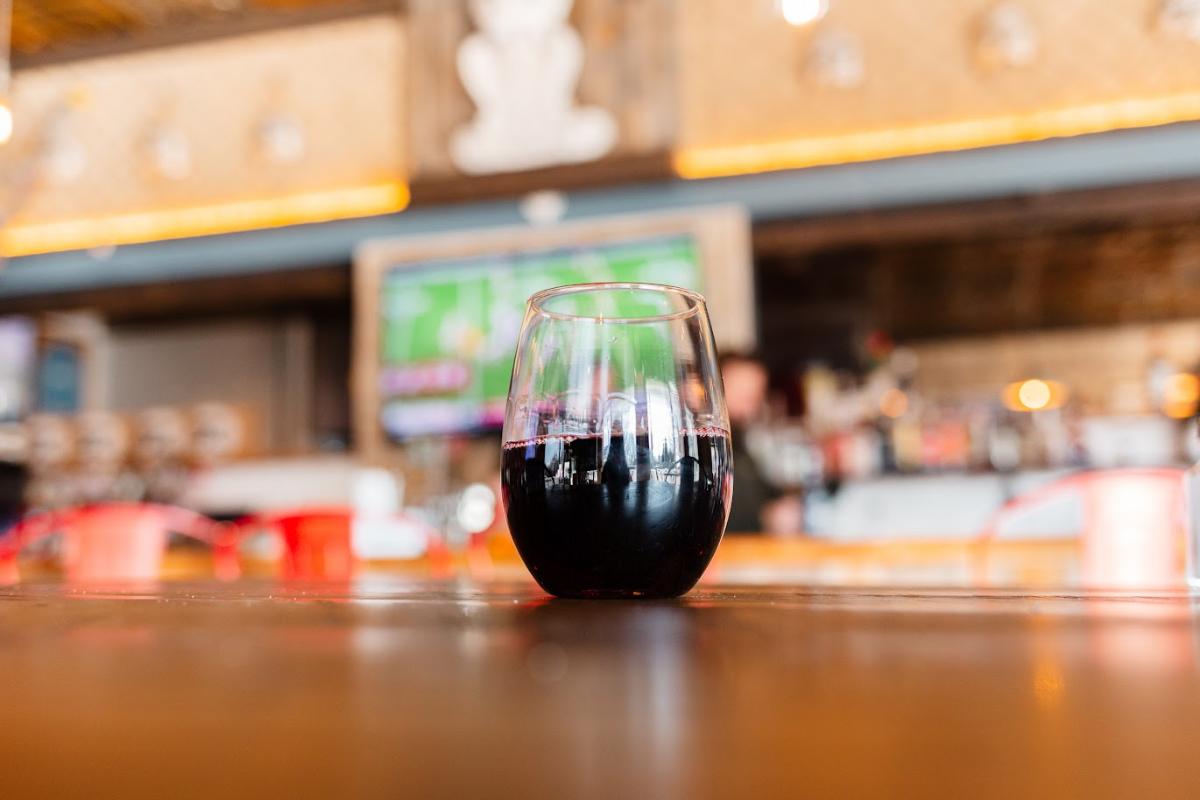 Single glass of red wine served on table with blurred bar background