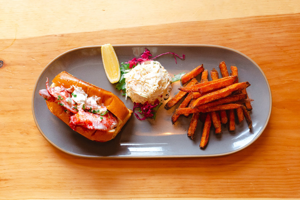 Lobster roll on plate with sweet potato fries
