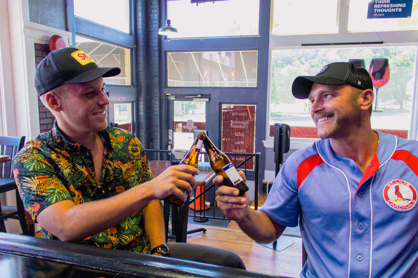 Two smiling guests clinking beer bottles