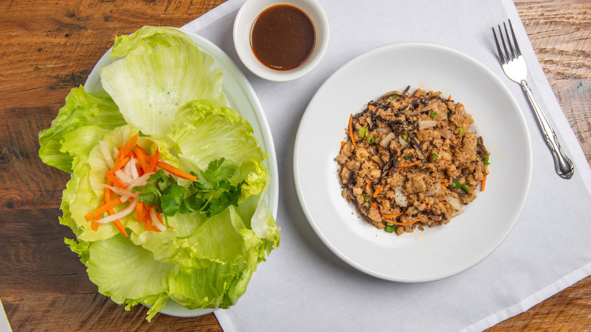 Cooked ground meat mixed with onion and carrot, served with a sauce dip and lettuce on a side