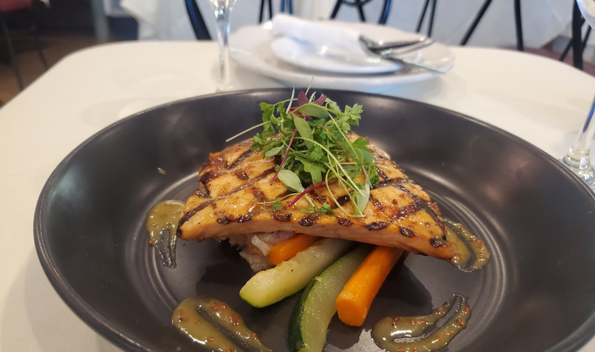 Grilled salmon atop cooked vegetables