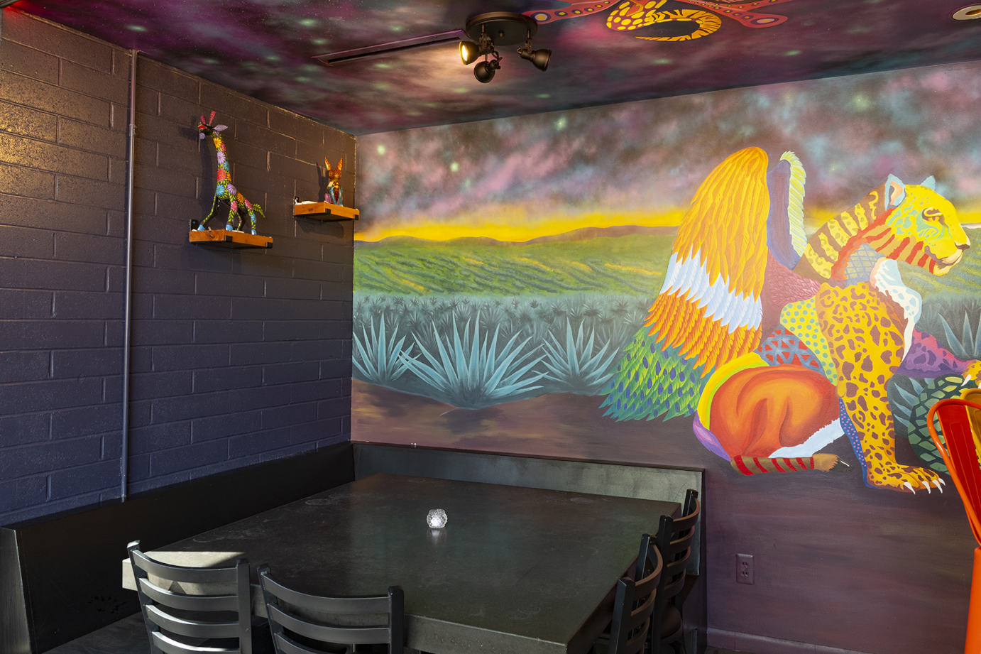 Table and seats by a wall decorated with colorful mural