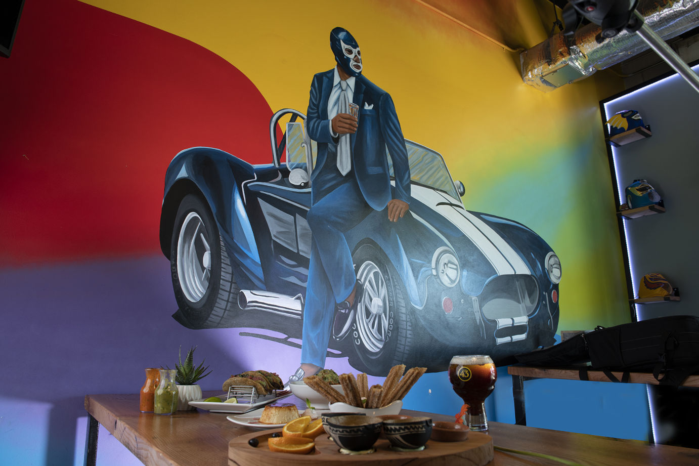 Interior, served food and drink on a table by a wall with mural art