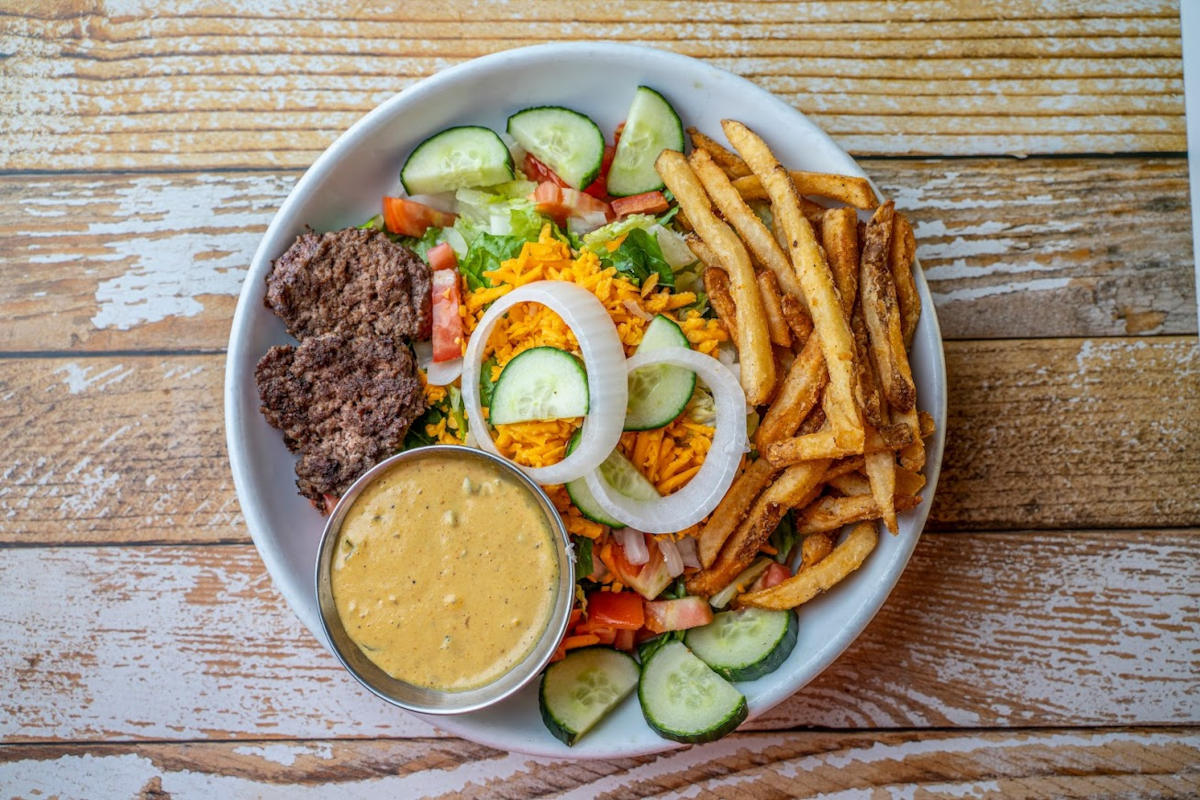 Chopped salad, fries and two patties with a dip