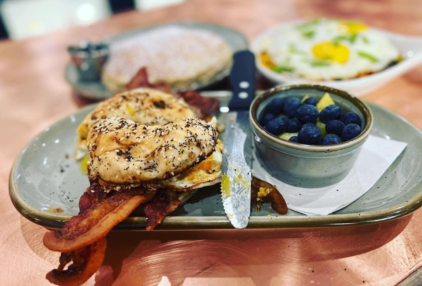 Egg, cheese and bacon bagel sandwich served with berry and fruit bowl