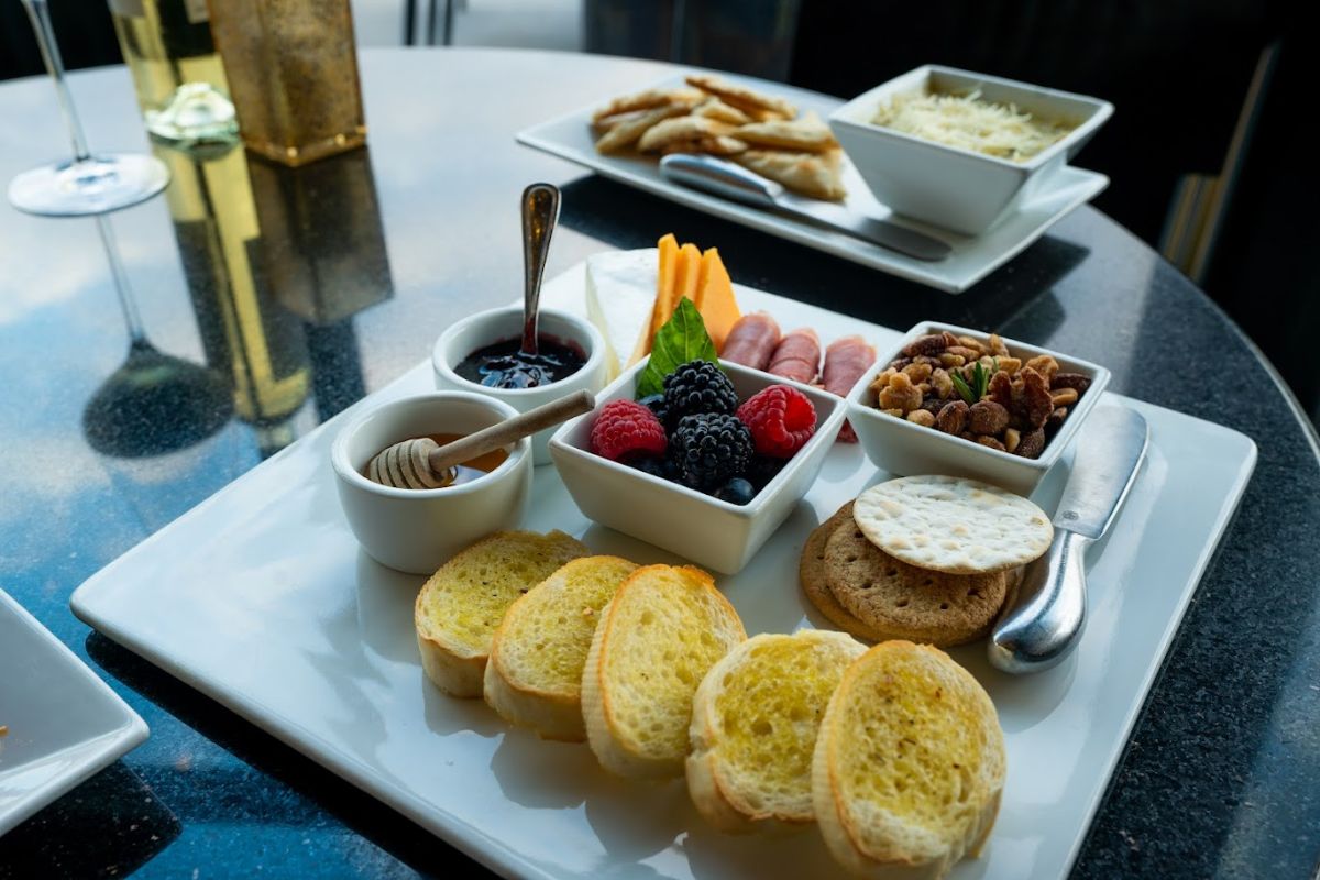 Platter with bread, honey, crackers, fresh fruit, nuts, sauce, cheeses and cured meat