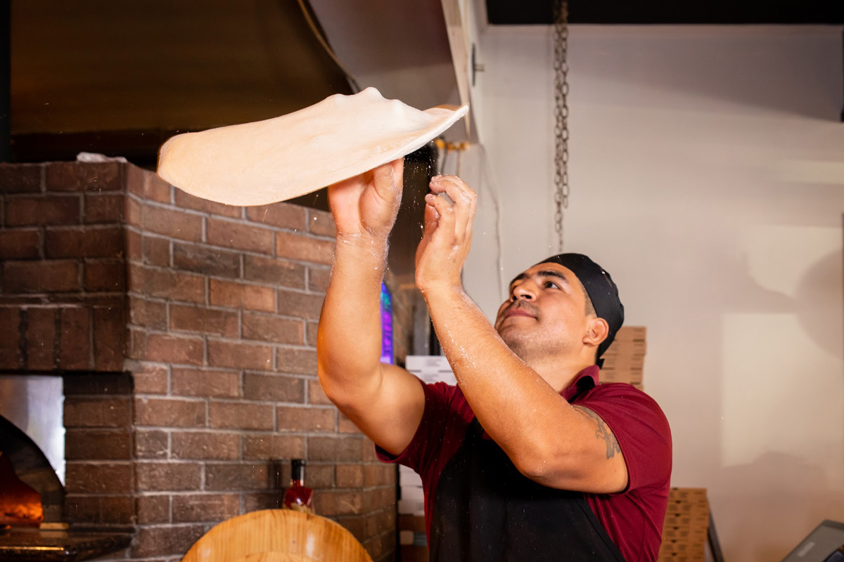 Pizza maker spinning pizza dough