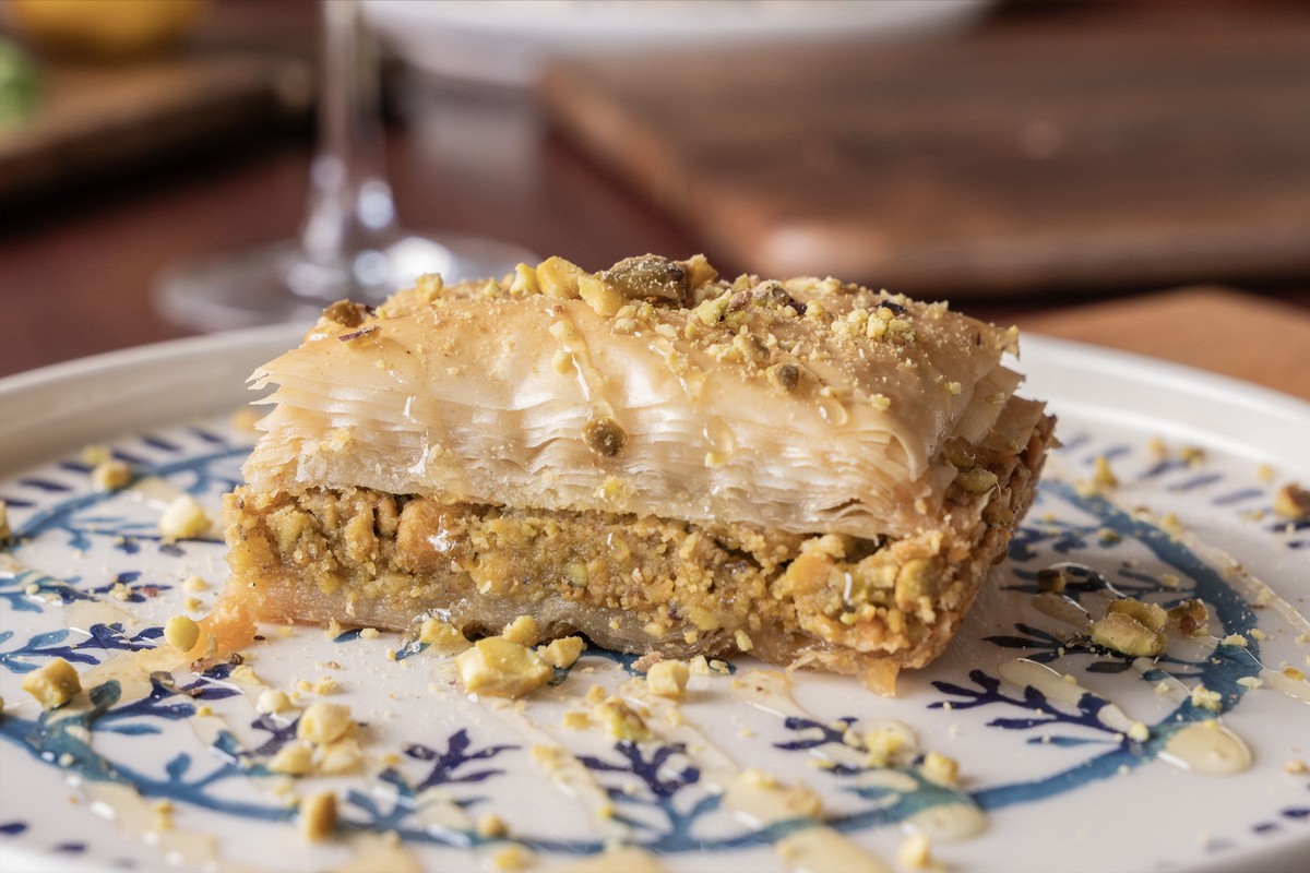 a piece of baklava on a plate with a glass of wine
