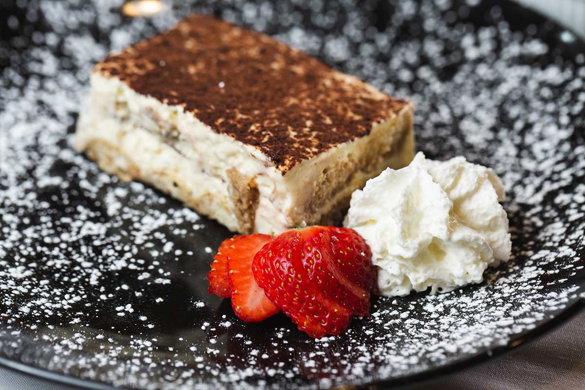 Tiramisu served with a strawberry and whipped cream