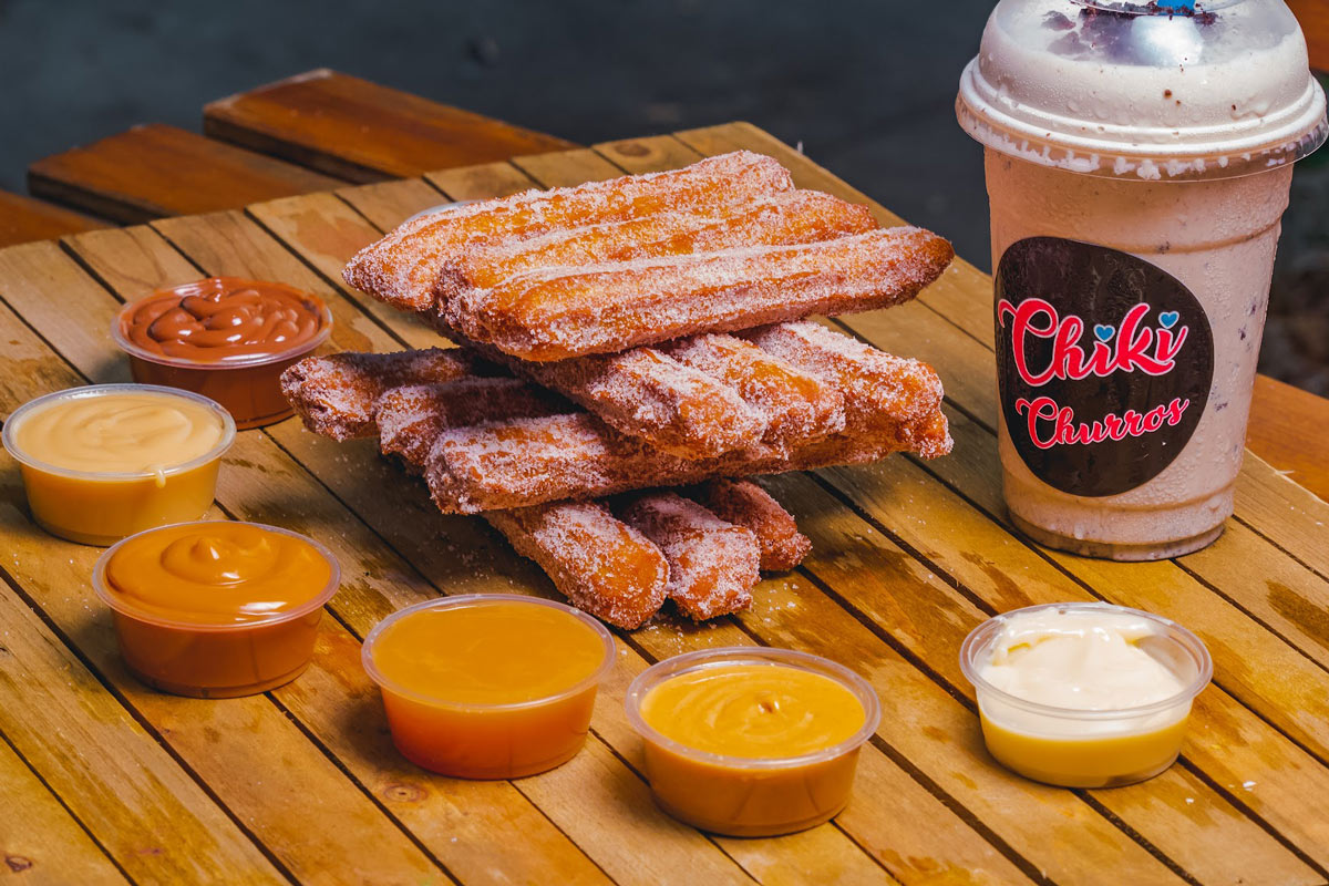 Stacked churros with various dipping sauces and milkshake on the table