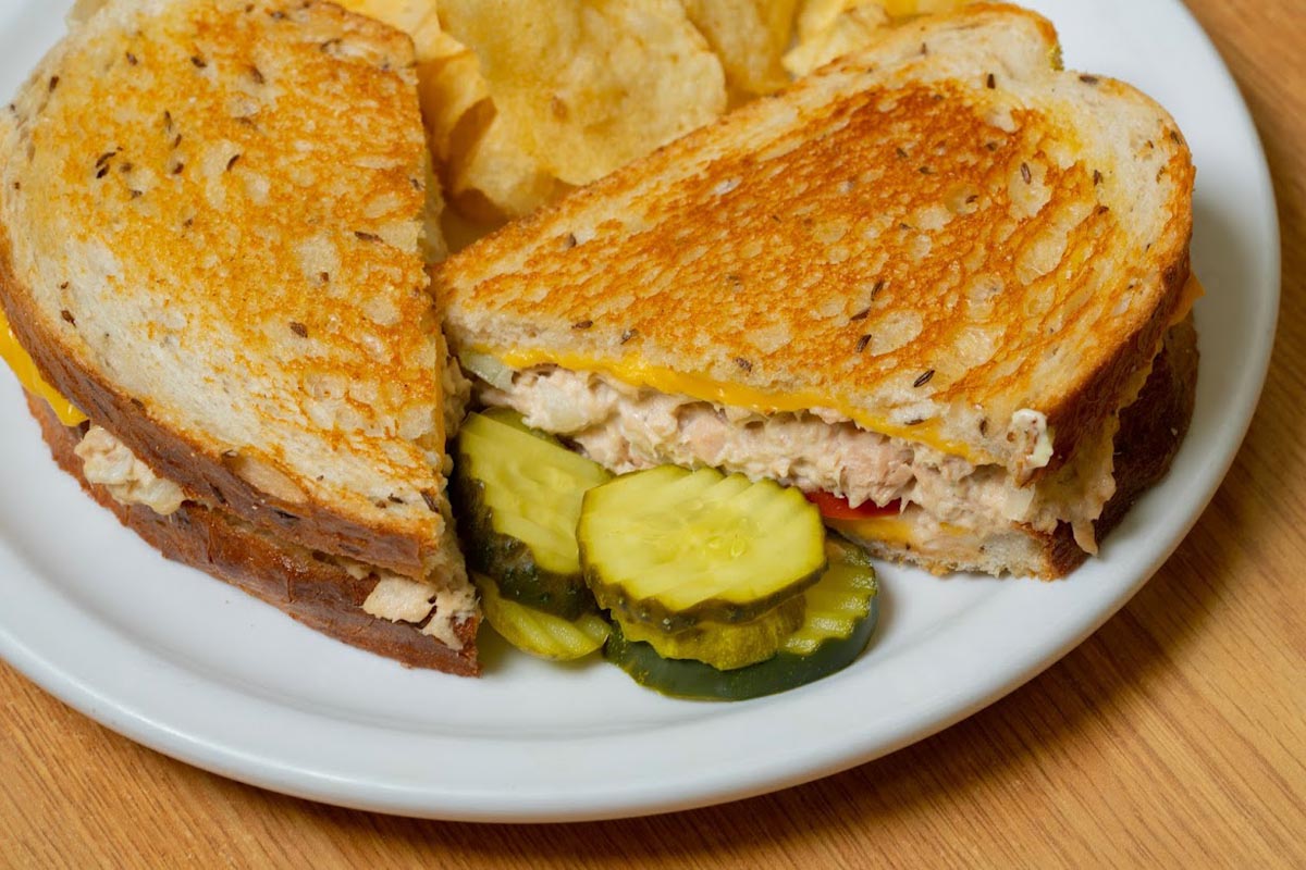 Tuna salad sandwich with chips and pickle