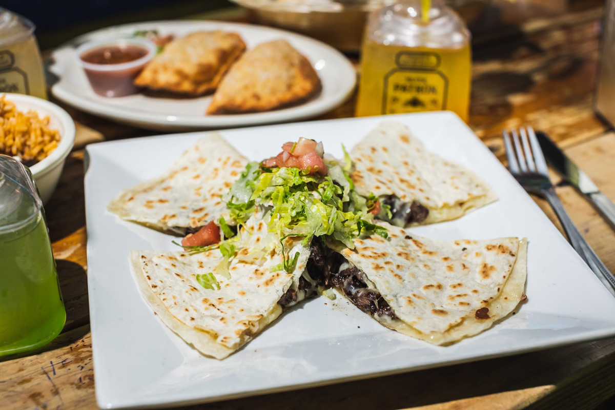Steak quesadilla served with various dishes and drinks