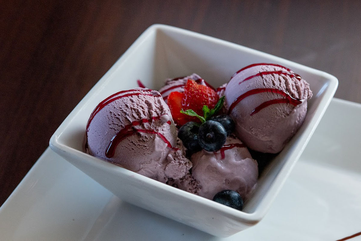 Blueberry ice cream bowl, garnished with fresh berries and drizzle