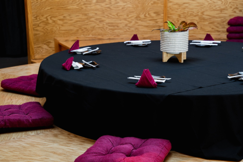 a table with a black tablecloth and purple pillows