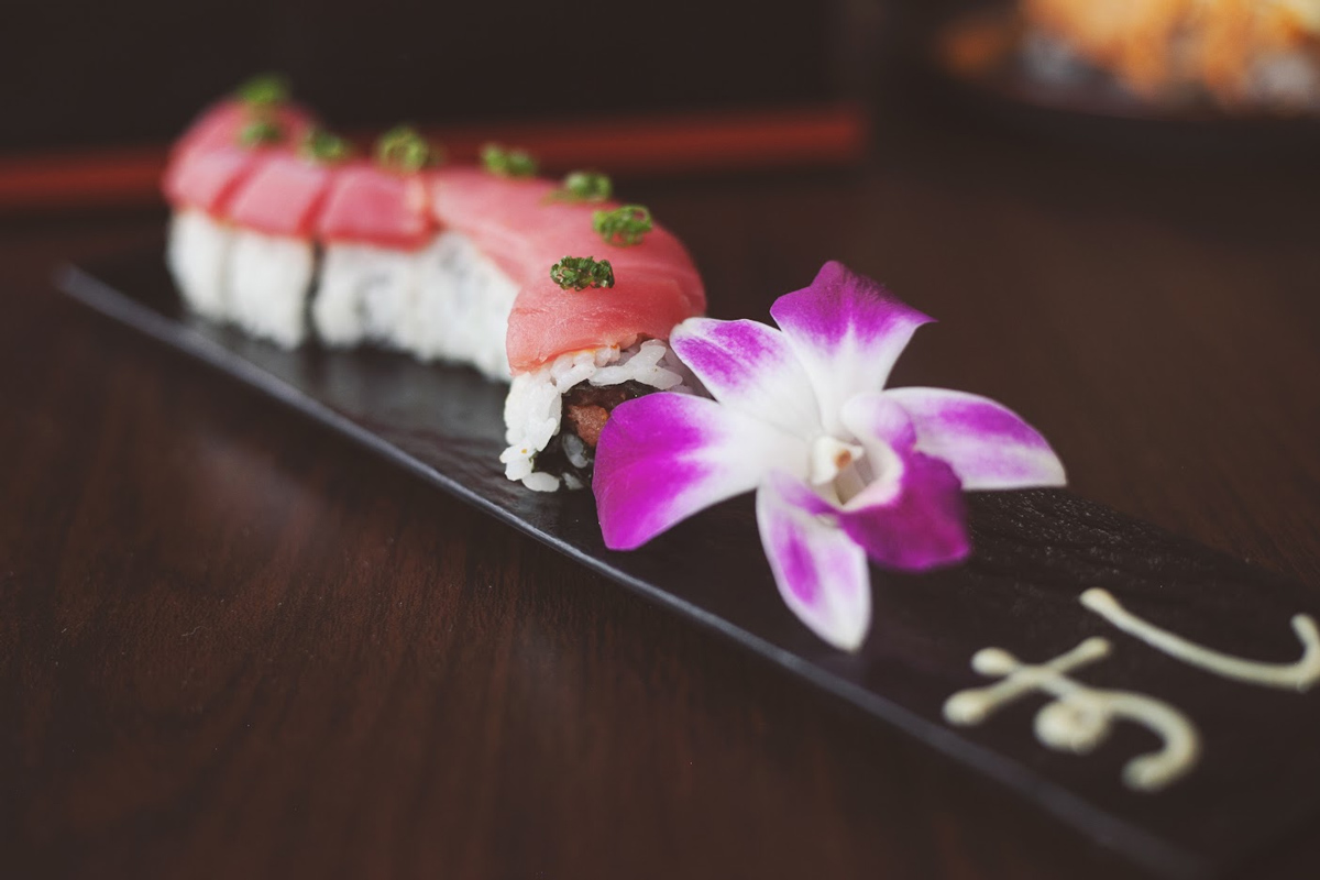 Tuna roll on a plate decorated with purple orchid flower 