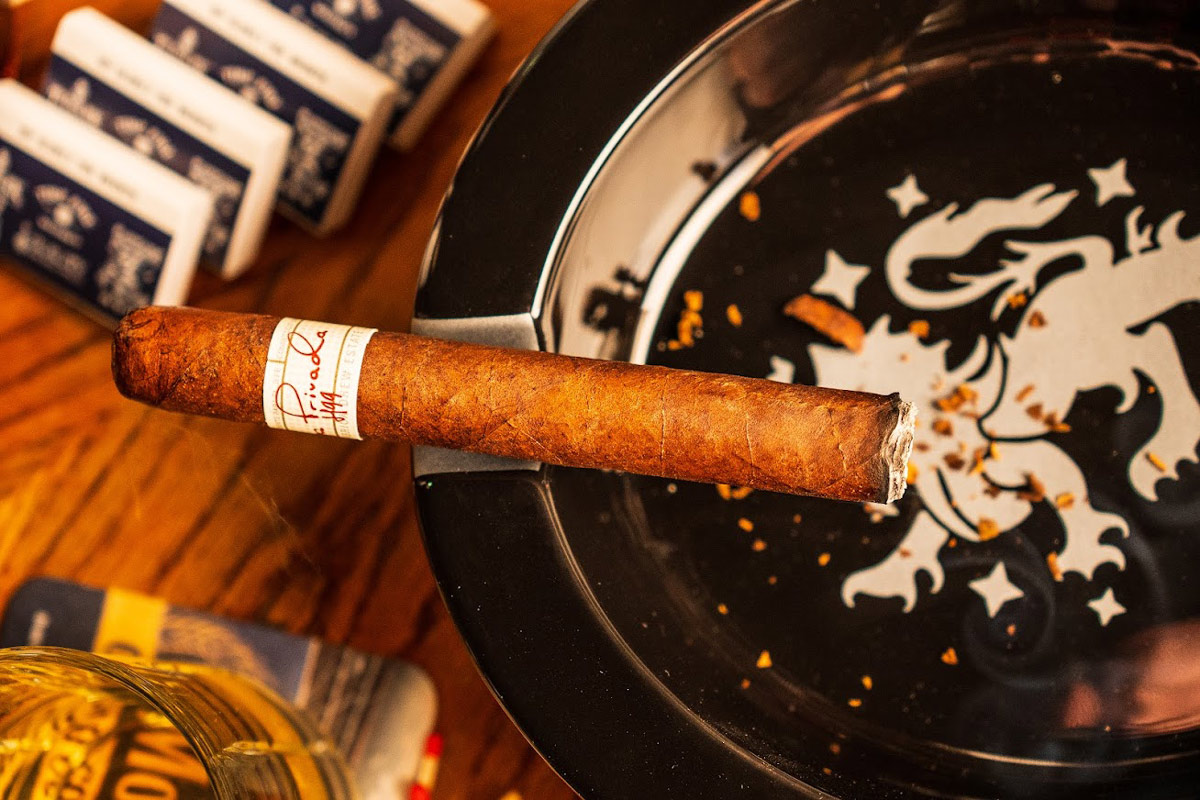 A lit cigar on an ashtray surrounded by various cigar accessory items, top view