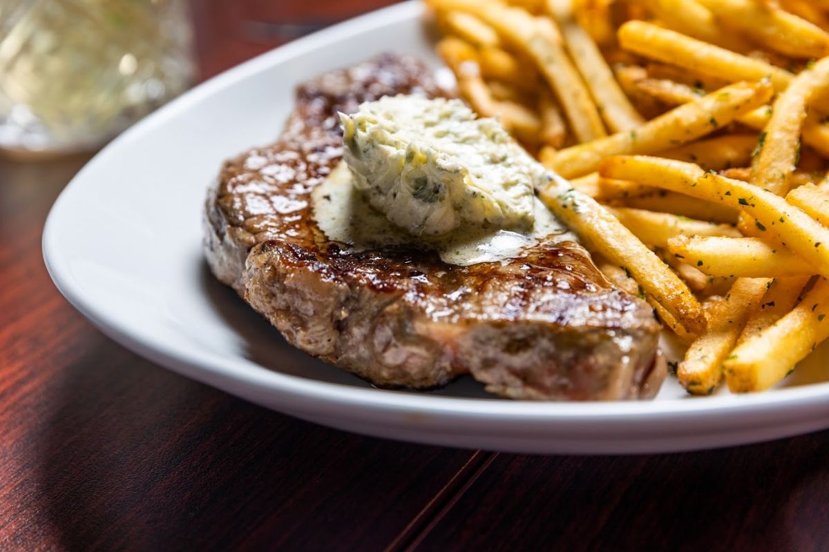 Steak topped with a sauce, served with fries