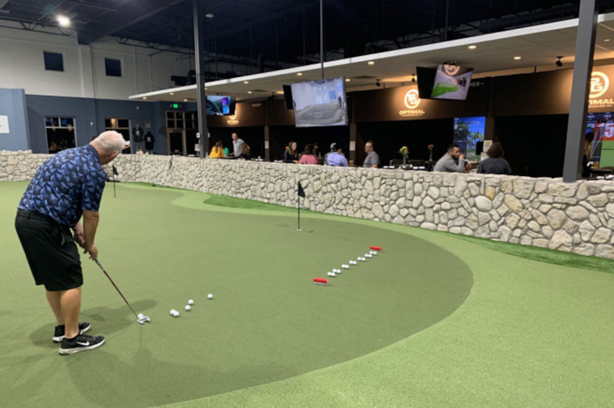 A person playing miniature golf in front of an audience