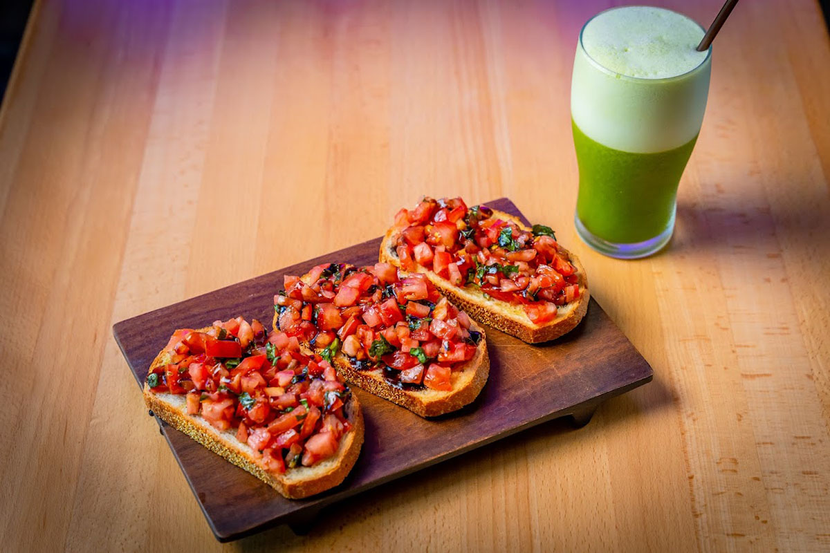Bruschetta board with  a glass of green juice on the table