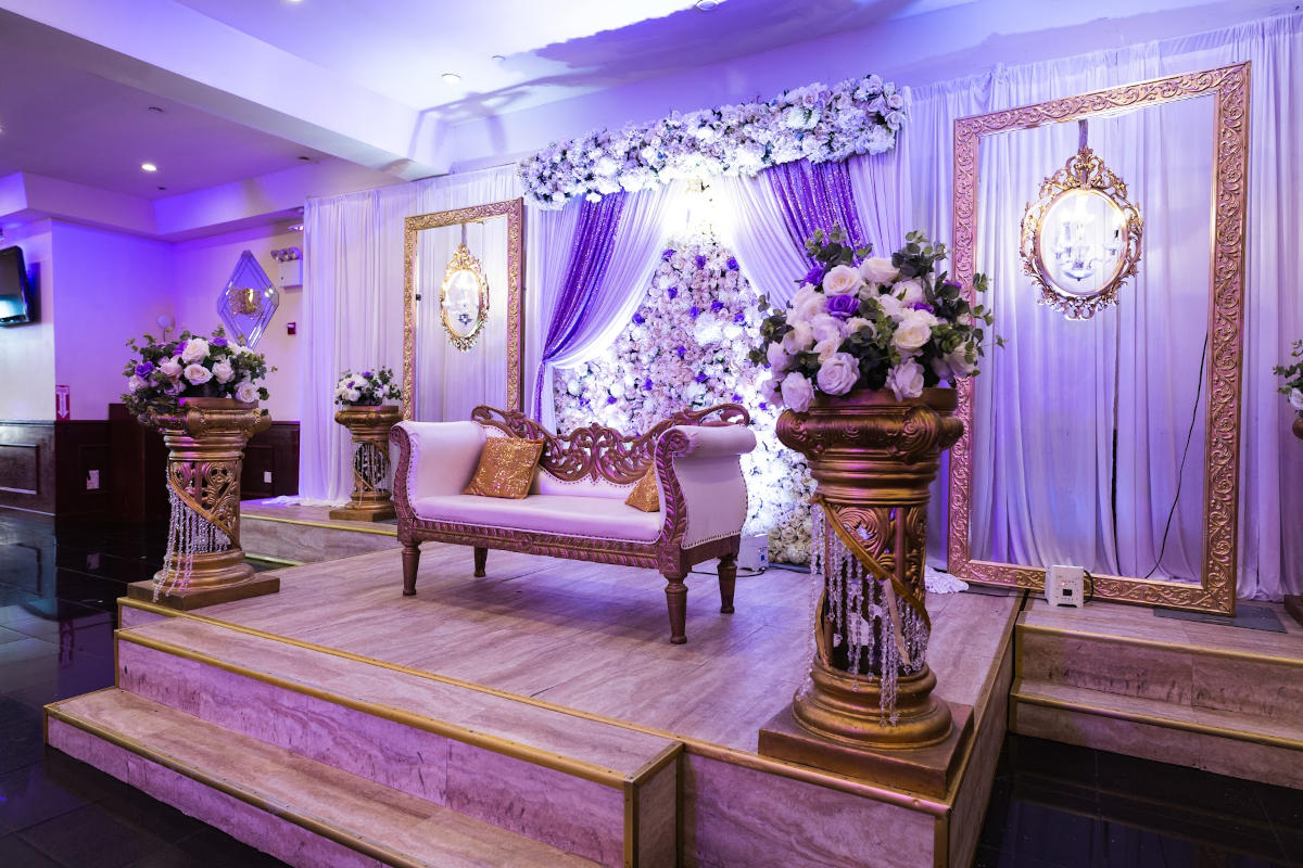 Interior, a podium with wedding sofa, flower column stands and floral wall decoration