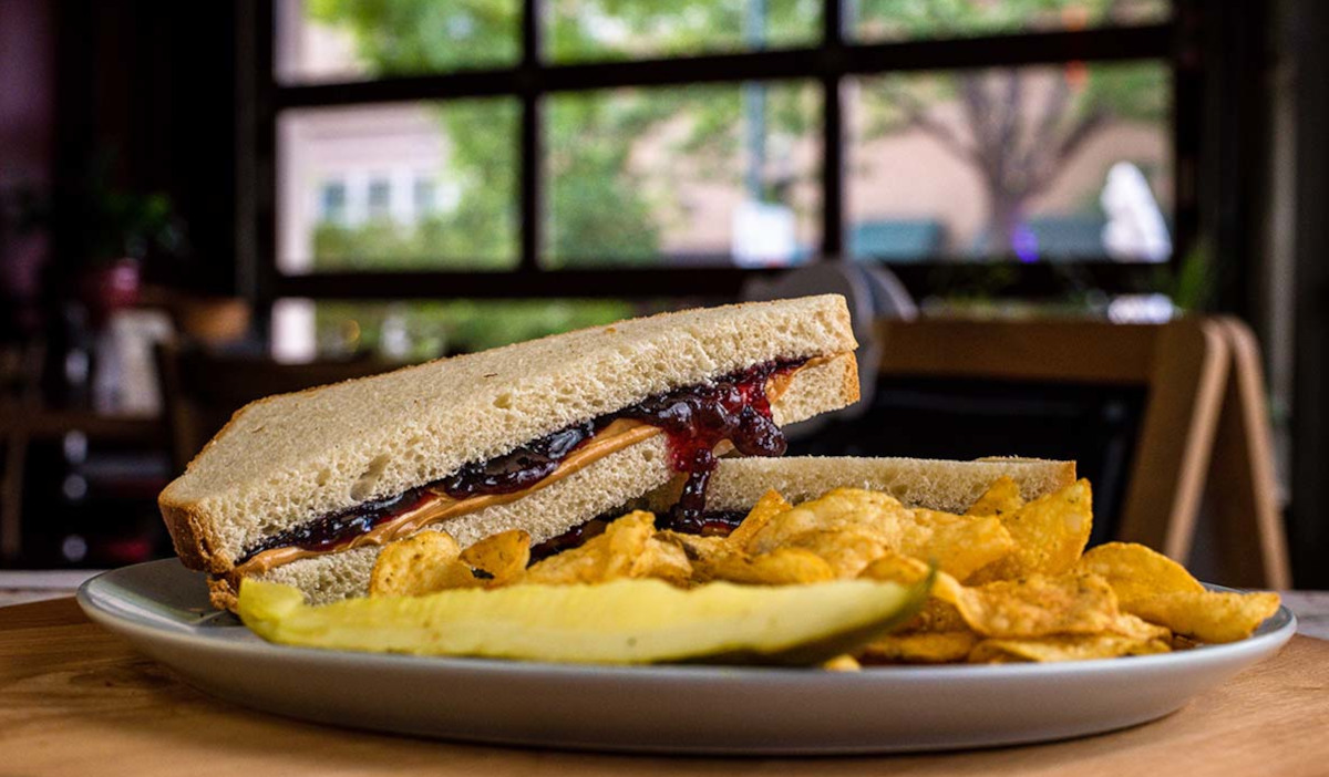 Peanut butter and jelly sandwich with chips and pickle