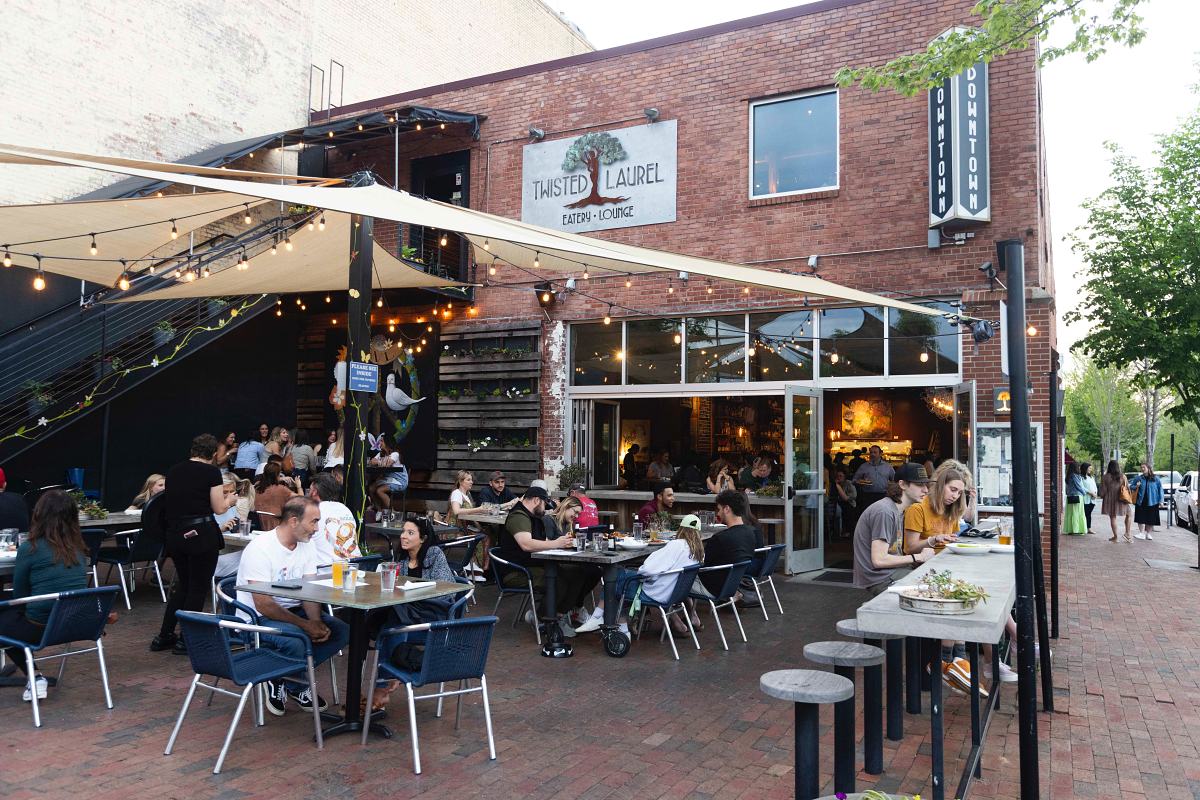 Outdoor pation with a group of people sitting at tables outside a restaurant