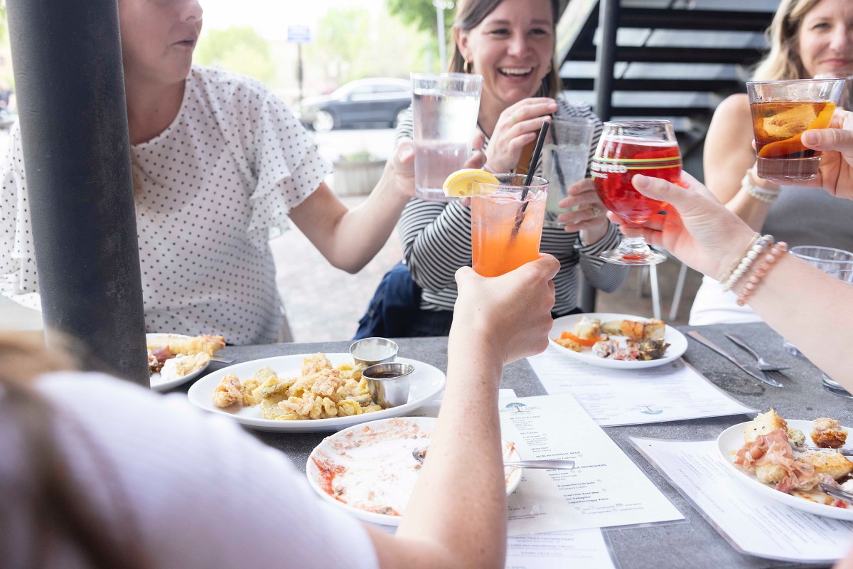 A casual group of women sitting at a table with food and drinks