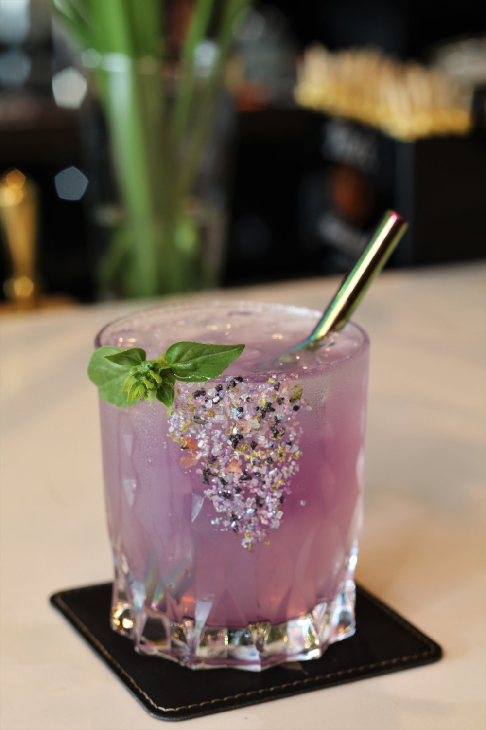 Purple cocktail served in a rimmed glass with leaf garnish