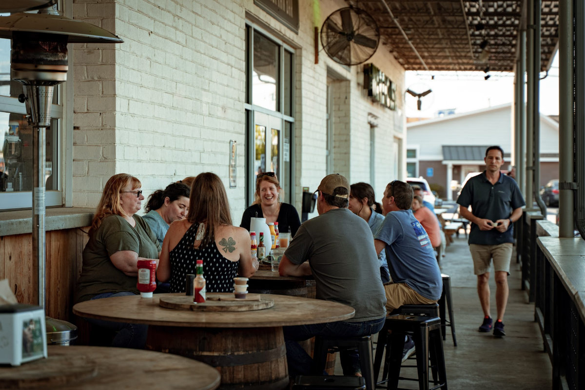 A group of people sitting at tables outside a building