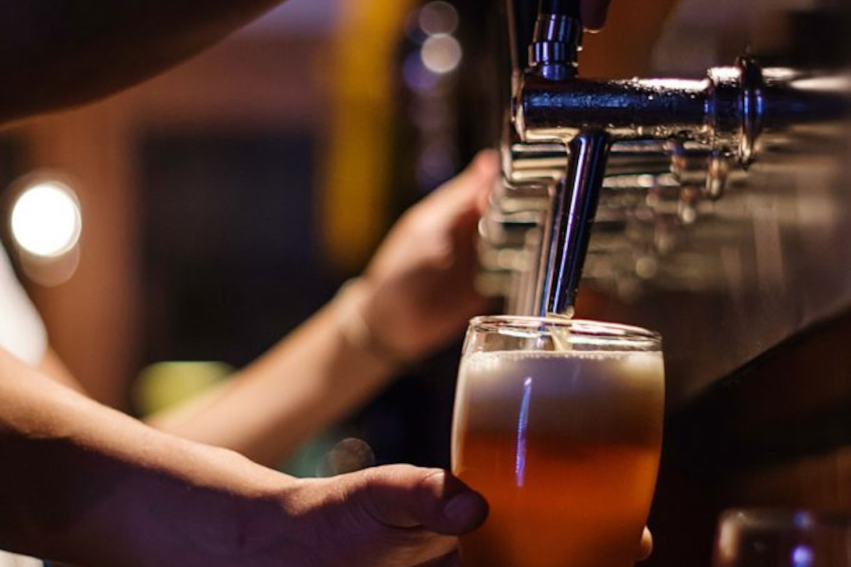 A person pouring a beer from a tap