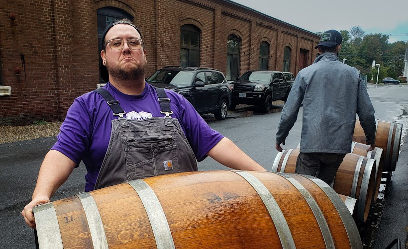 A person holding a very large wooden keg