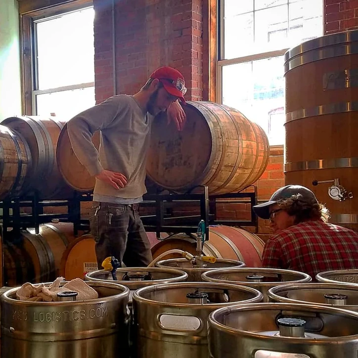 Team members in action  by kegs and barrels 