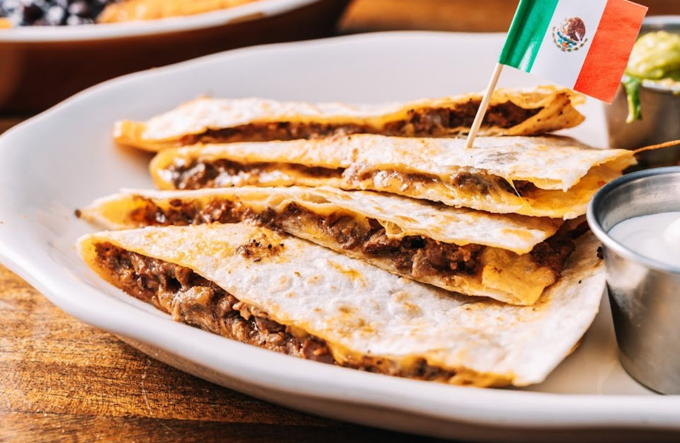 Closeup of a plate of quesadillas with a small Mexican flag