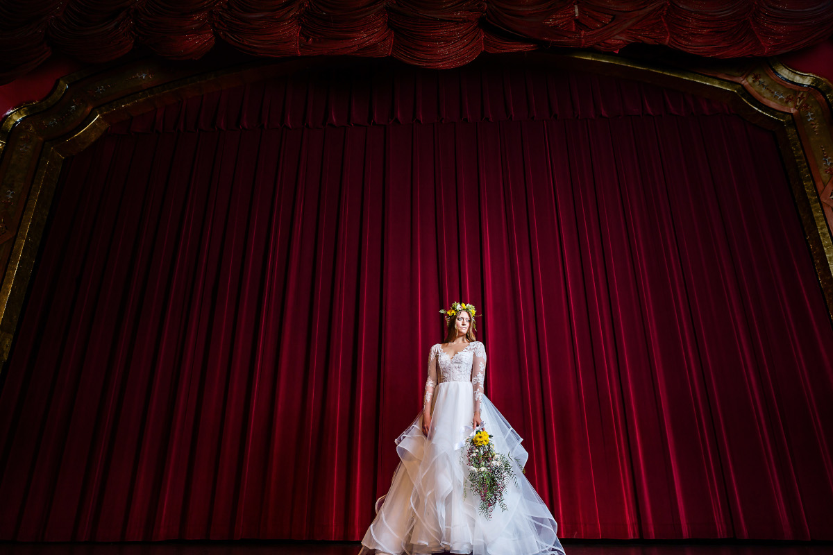 A bride standing on a theater stage with flowers in hand