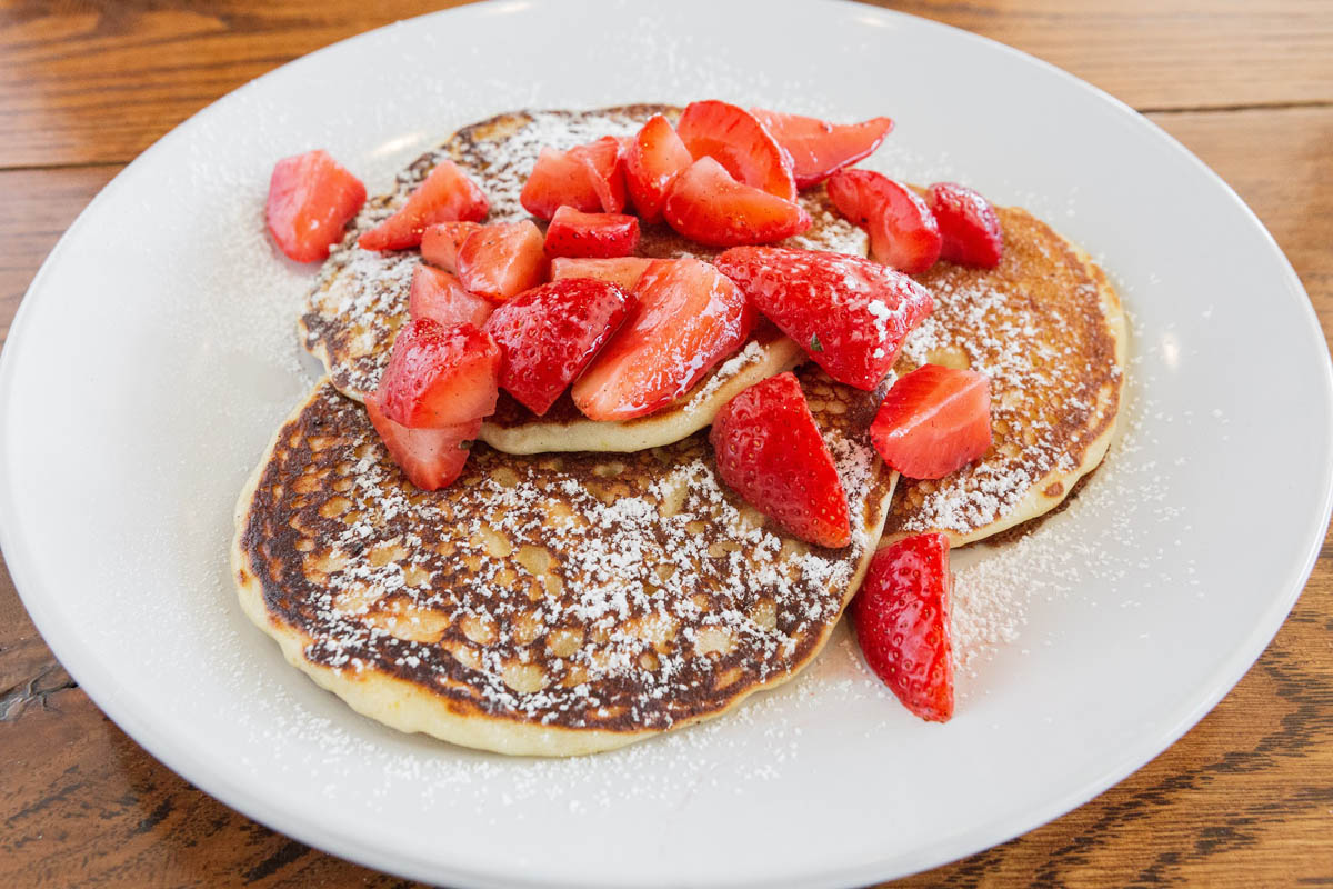 Almond pancakes topped with powdered sugar and strawberries