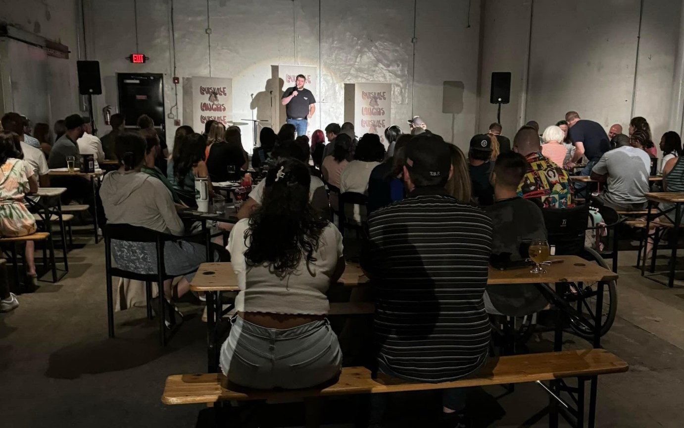 A man delivers a speech on stage, with an attentive audience watching