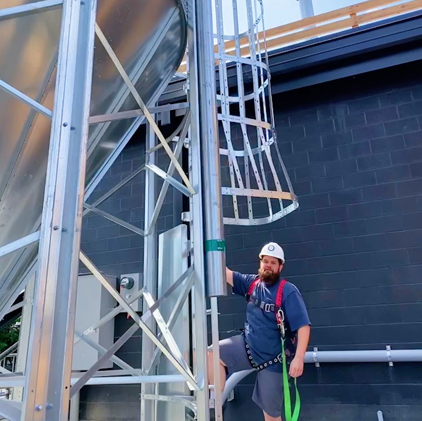 Employee standing by a cage ladder outside