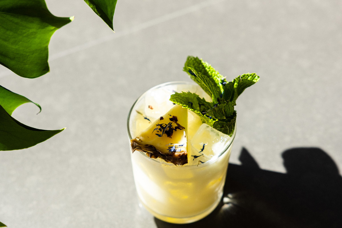 Cocktail drink with pineapple and mint leaf garnish